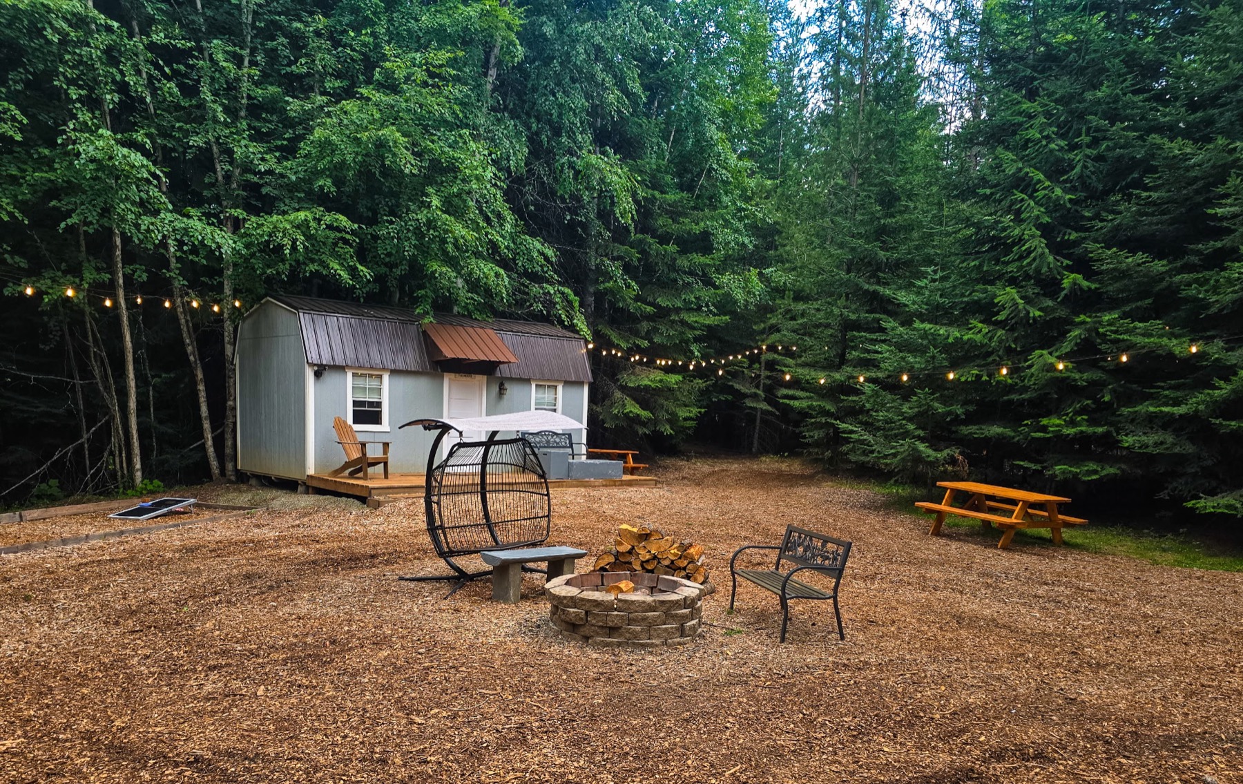 The Village at dusk - cabin, fire pit, string lights